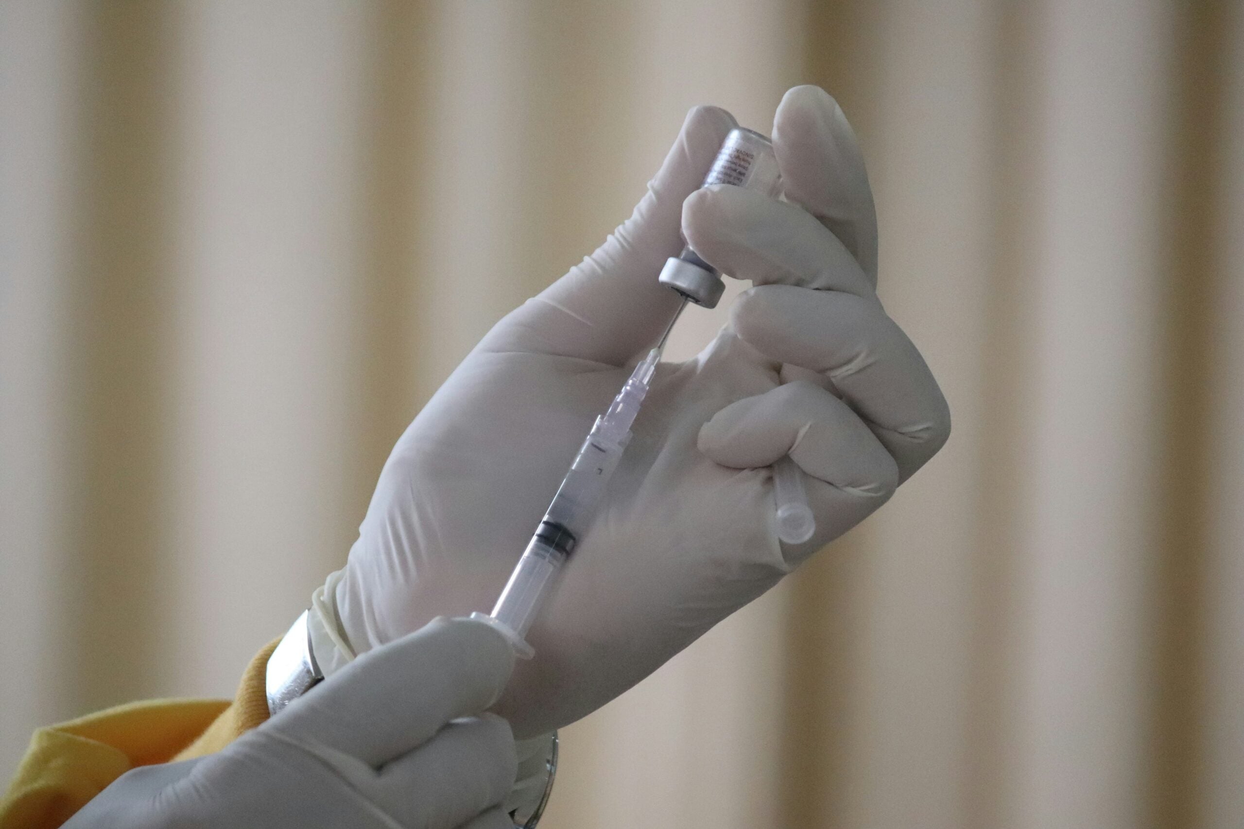 Close up of a syringe being filled from a vaccine vial